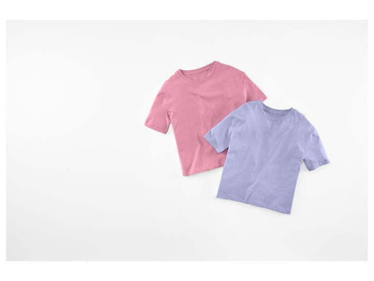 Twee kinder-T-shirts, één roze en één paars, liggen op een witte achtergrond.