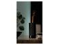 Zwarte aroma diffuser met vlam-effect en stoom, naast een plant op een houten tafel.