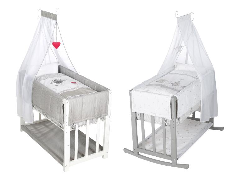 Twee babybedjes met hemel, één wit en één grijs, met bijpassend beddengoed.