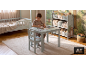 Jongen tekent aan een kindertafel met stoel in een kamer met bed en speelgoedrek.