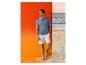 Man in blauwe gebreide poloshirt en witte short op het strand.