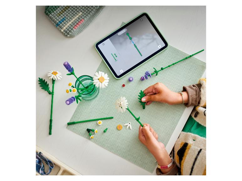 Kind assembleert een bloemenboeket van bouwstenen, volgt instructies op een tablet.