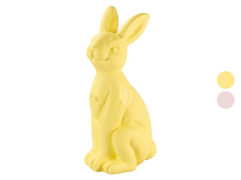 Gele paashaasfiguur met twee kleurstaaltjes rechts.