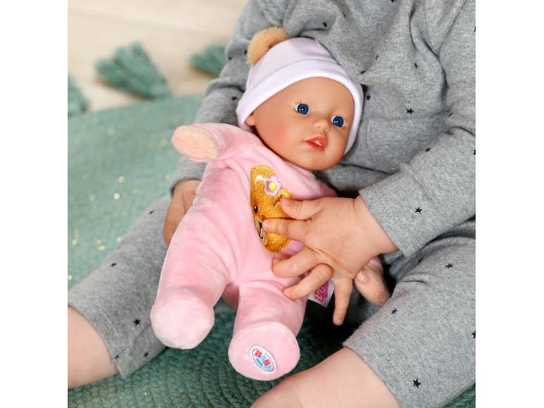 Een kind houdt een babypop vast in een roze kruippakje en een wit mutsje.