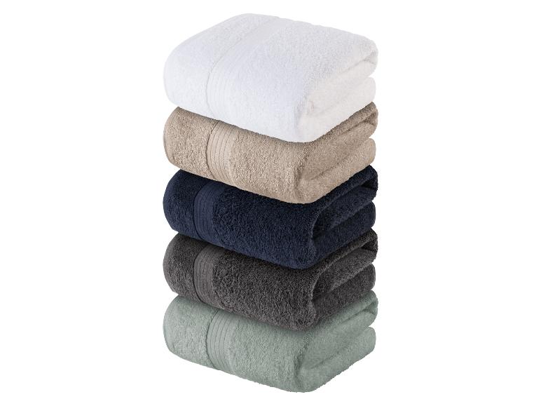 Stapel badhanddoeken: wit, beige, donkerblauw, donkergrijs en saliegroen.