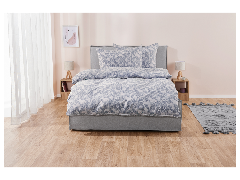 Damast beddengoed in blauwe tinten op een grijs bed.