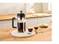 French press, twee kopjes koffie en koekjes op een houten tafel in de keuken.