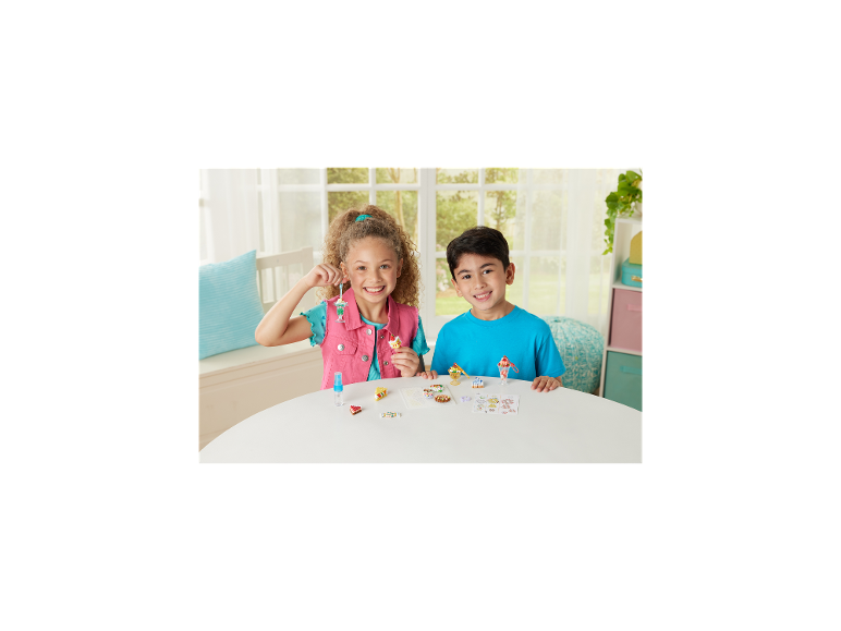 Twee lachende kinderen met knutselcreaties van miniatuurdesserts en etenswaren.