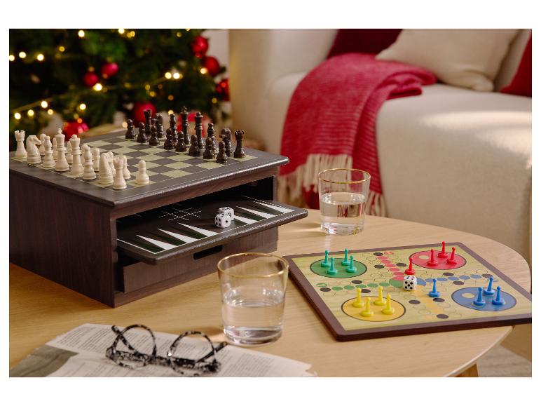 Bordspellen, waaronder schaken, backgammon en Ludo, op een salontafel naast een kerstboom.