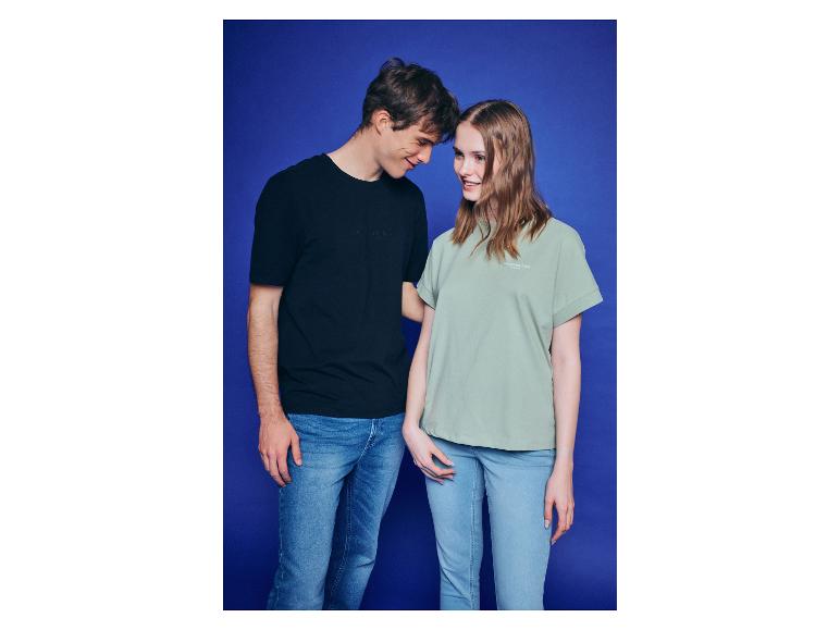 Lachende man en vrouw in T-shirts en jeans, tegen een blauwe achtergrond.