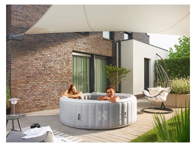 Twee mensen genieten van een bubbelbad op een terras, met een zonnescherm erboven.