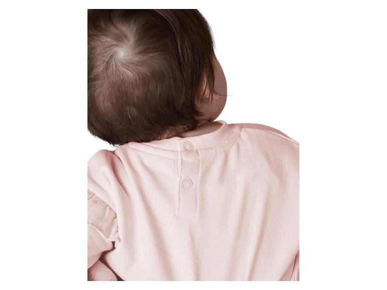 Achterkant van babyhoofd en roze shirt met drukknopen.