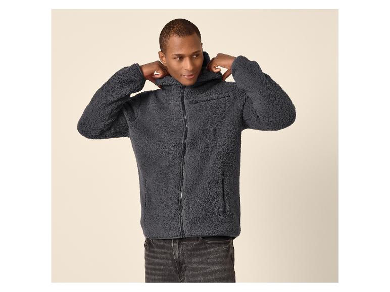 Man in grijs fleecevest met capuchon en zwarte jeans.