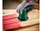 Een gehandschoende hand schuurt een rode houten plank met een excenterschuurmachine.