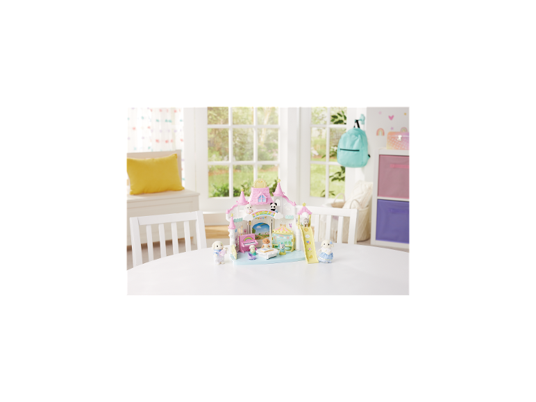 Kinderdagverblijf speelset met roze kasteel, speelgoeddieren en accessoires op een witte tafel.