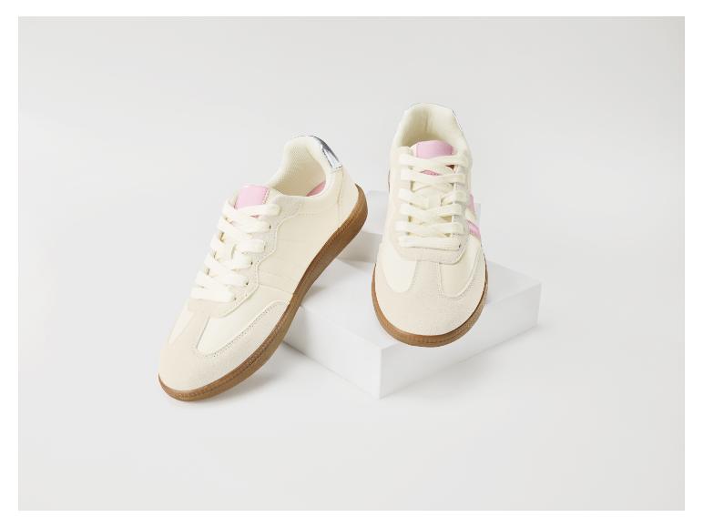 Beige sneakers met roze accenten en bruine rubberen zool op een wit blok.