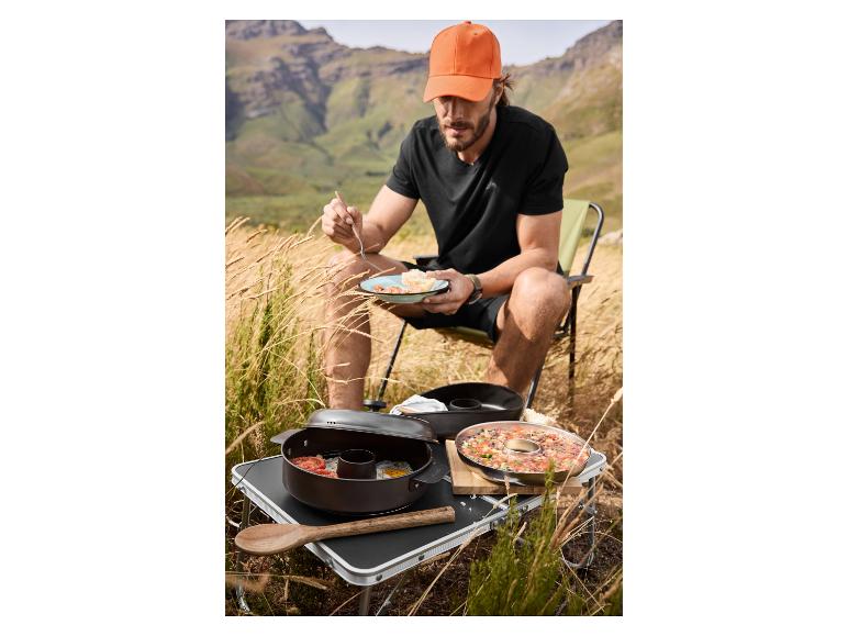 Man eet tijdens het kamperen met kookgerei en eten op tafel.