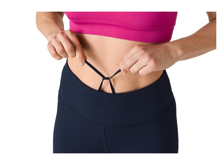 Vrouw die de koordjes van een sportlegging en roze top aanpast.