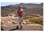 Man in wandel-T-shirt en korte broek met trekkingstokken in een berglandschap.
