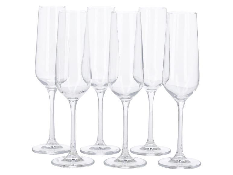 Zes heldere champagneglazen met steel op een witte achtergrond.