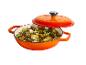 Oranje gietijzeren braadpan met deksel, gevuld met gebakken aardappelen, champignons en lente-uitjes.