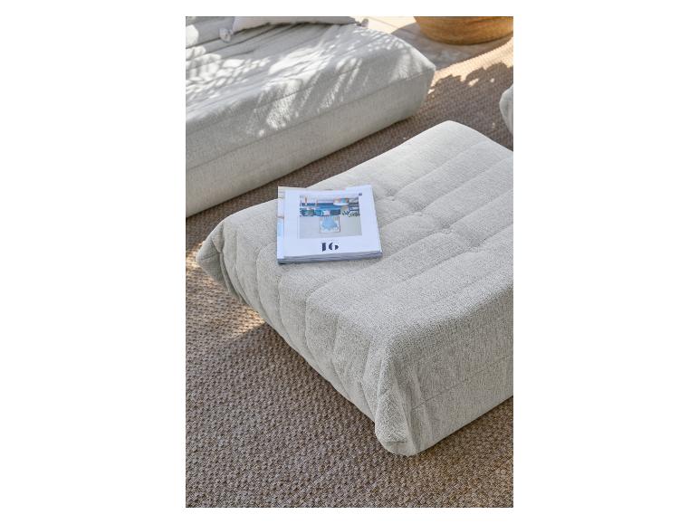 Lichtgrijze gestoffeerde poefs op een geweven vloerkleed, met een tijdschrift erop.