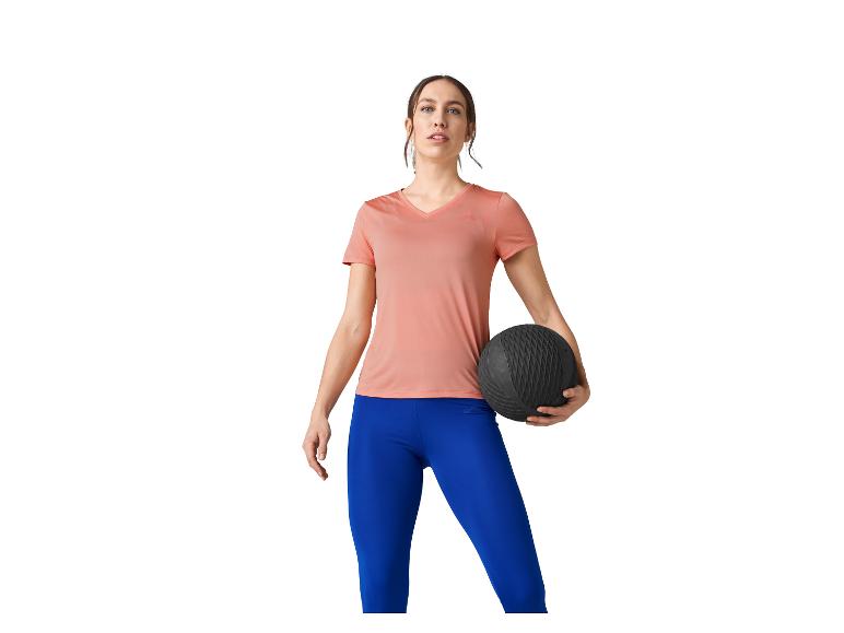 Vrouw in roze shirt en blauwe leggings houdt een oefenbal vast.