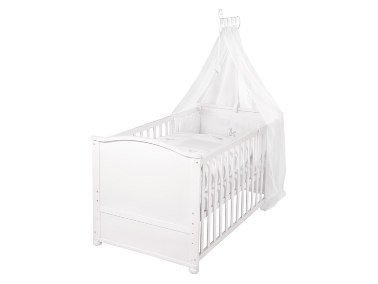 Een wit babybedje met een hemel.