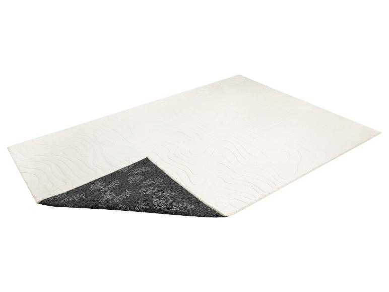 Gebroken wit badmatje met golvend patroon en donkergrijze antislip onderkant met bloemmotief.