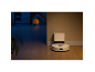 Robotstofzuiger met laadstation op houten vloer, half in licht, half in donker.