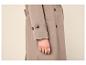 Beige jas met knopen en een hand met een gouden ring.