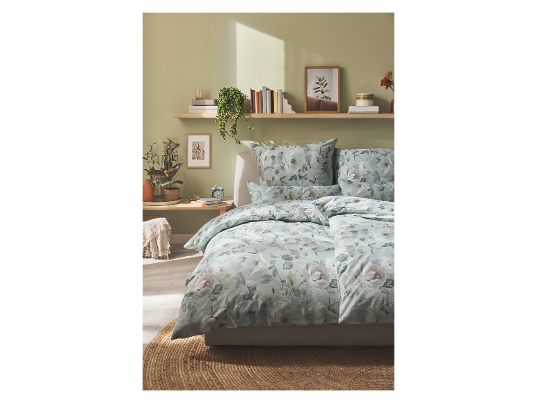 Bloemen beddengoed in groene en roze tinten op een bed met nachtkastje.