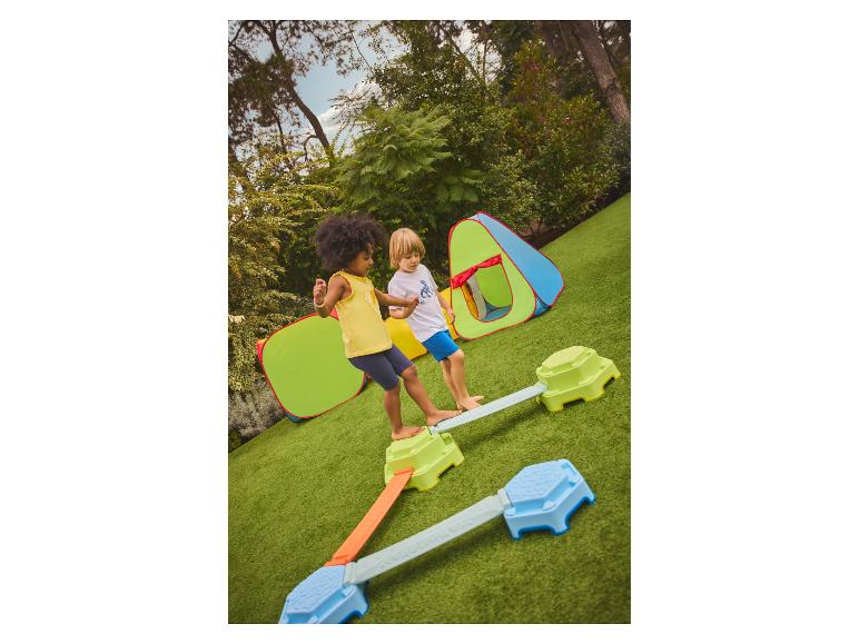 Kinderen spelen op een evenwichtsbalk buiten met speeltenten.