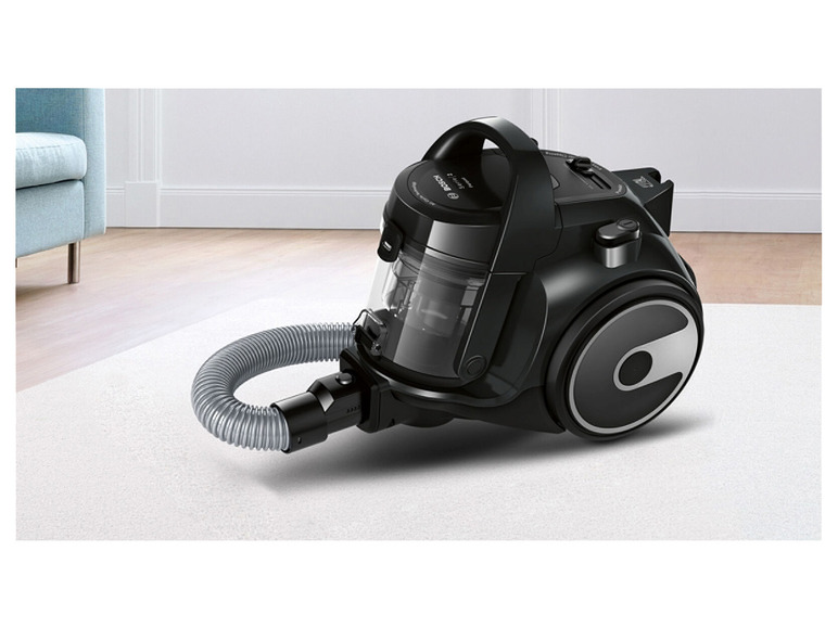 Een zwarte Bosch stofzuiger met een slang op een witte vloerbedekking.