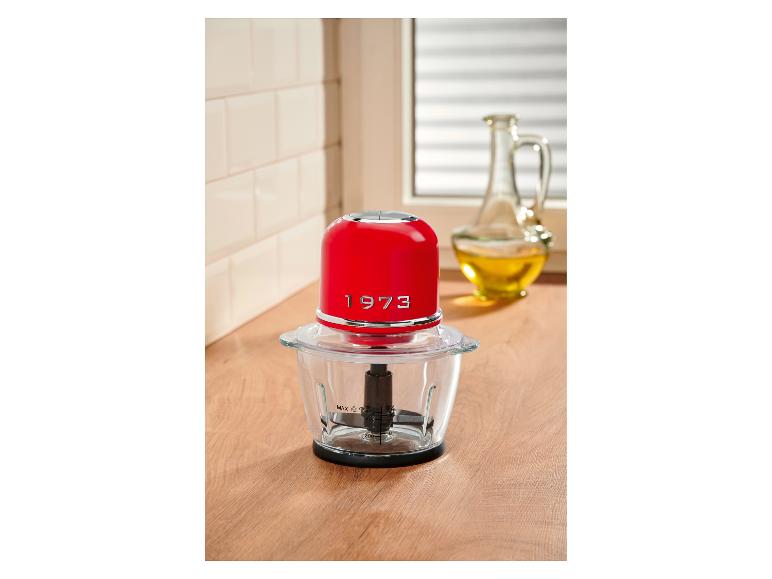 Rode hakmolen op een houten aanrecht met een fles olie op de achtergrond.