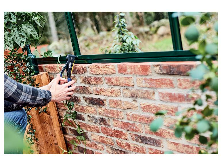 Persoon gebruikt LIVARNO® blindklinknageltang op bakstenen muur in kas.