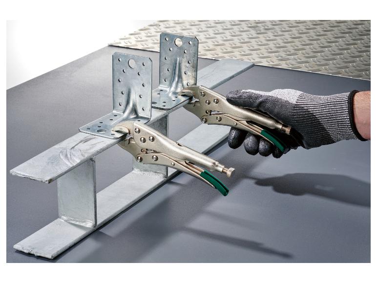 Hand houdt metalen beugel vast met tang, bevestigd aan metalen profiel.