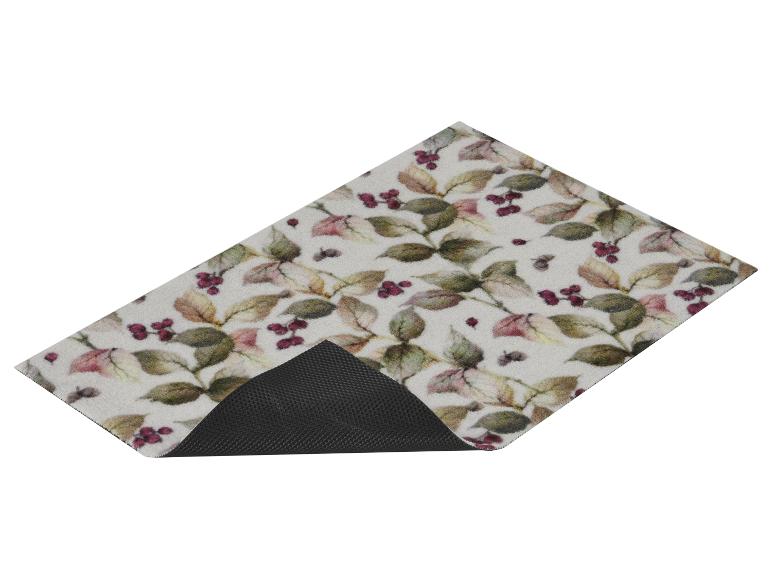 Geprint vloerkleed met bladeren en bessen, met zichtbare zwarte antislip onderkant.
