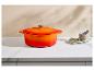 Oranje geëmailleerde gietijzeren braadpan op een aanrecht met een vijzel en laurierblaadjes.