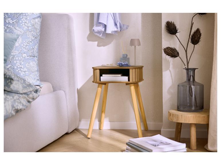 Slaapkamer met een houten nachtkastje, een grijs bed en een vaas met gedroogde bloemen.