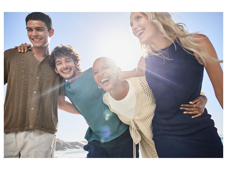 Lachende vrienden in casual kleding bij het strand.