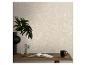 Beige behang met witte takpatronen, met een bureau en een plant.