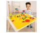 Blij kind speelt met boetseerklei en accessoires op een gele mat.