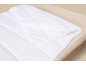Wit dekbed met drukknopen op een bed met een lichtbeige hoeslaken.