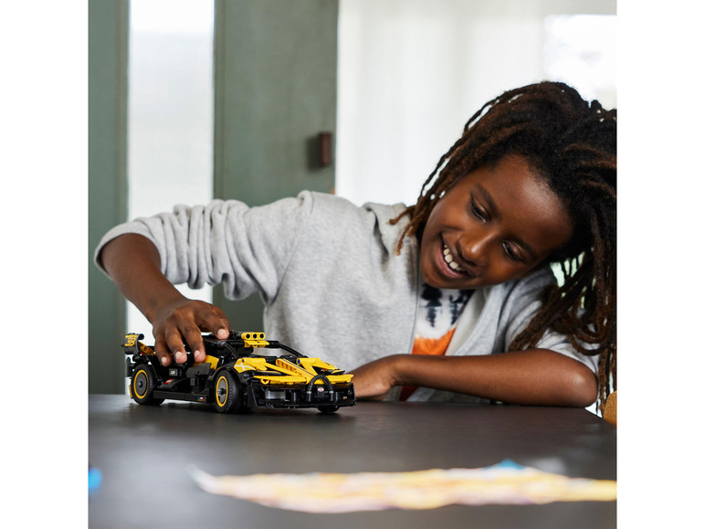 Een kind speelt met een gele LEGO Technic McLaren Senna model.