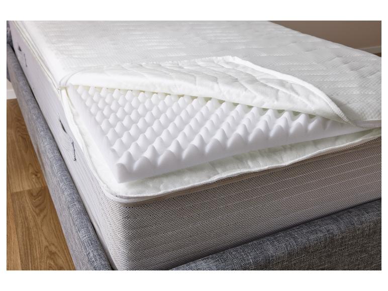 Een matras met een topper van schuim en een grijze bekleding.