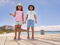 Twee kinderen dragen zomerkleding met zeedierenmotief op een houten pier.