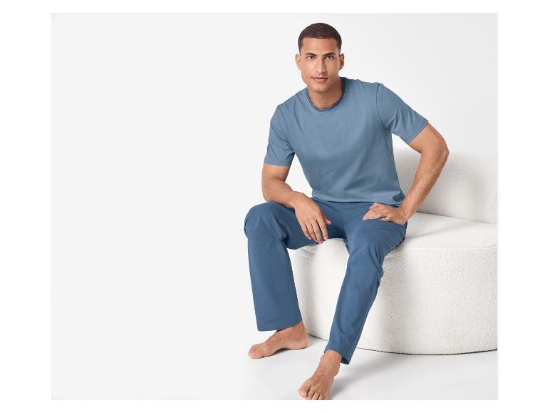 Man in blauw T-shirt en broek zit op een witte stoel.