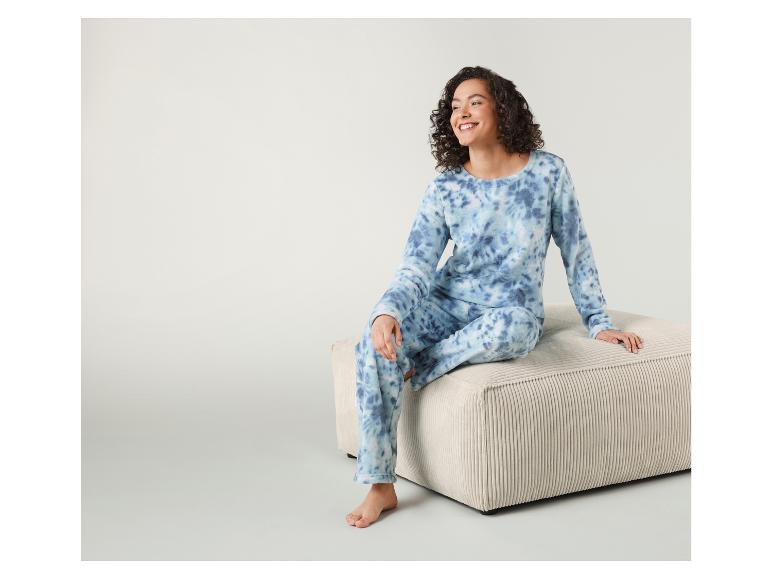 Een vrouw draagt een blauwe tie-dye pyjamabroek en een bijpassend shirt.