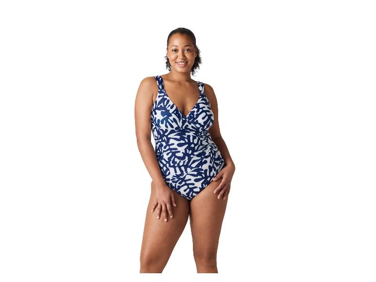 Vrouw in een badpak uit één stuk met een marineblauw en wit patroon.